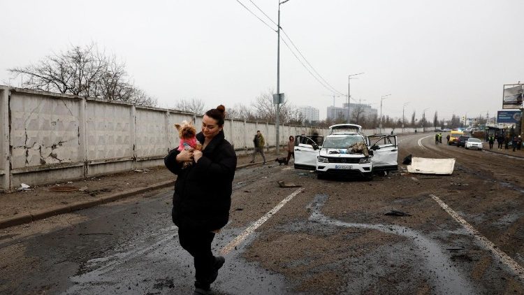 Uma mulher caminha com um cachorro no colo perto de um carro danificado, após um ataque russo com mísseis e drones contra Kiev, em meio ao ataque da Rússia à Ucrânia, em 29 de novembro de 2025. REUTERS/Valentyn Ogirenko