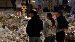 Persone in raccoglimento davanti ai fiori per le vittime dell'attentato di Bondi beach