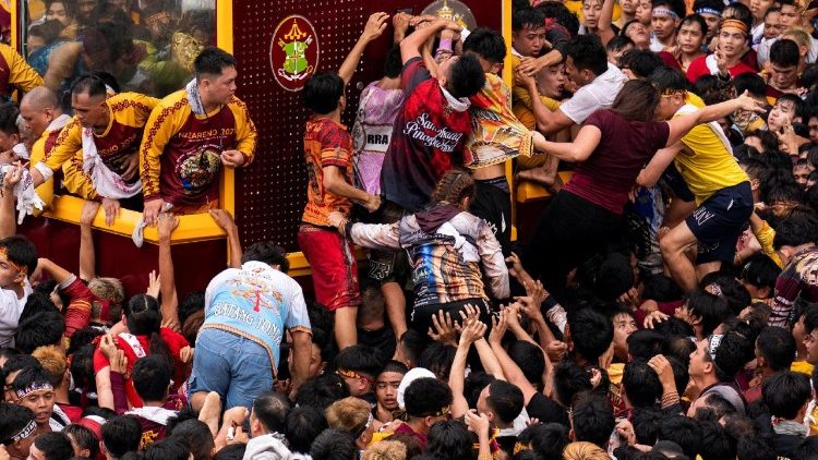 Pilgrims try to touch the carriage or climb onto it during the procession