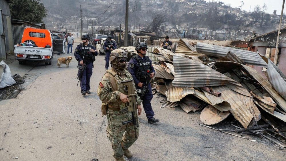Um membro da Infantaria da Marinha espanhola e um membro da Marinha chilena caminham ao lado de prédios destruídos, após um incêndio florestal na região de Biobío, onde múltiplos focos de incêndio provocaram evacuações de emergência, em Concepción, Chile, em 19 de janeiro de 2026. REUTERS/Juan Gonzalez