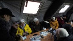 People warm up in a tent provided by emergency services for residents whose apartments are left without heating in Kyiv