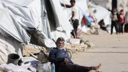 Displaced Palestinian man sits outside his tent in Gaza