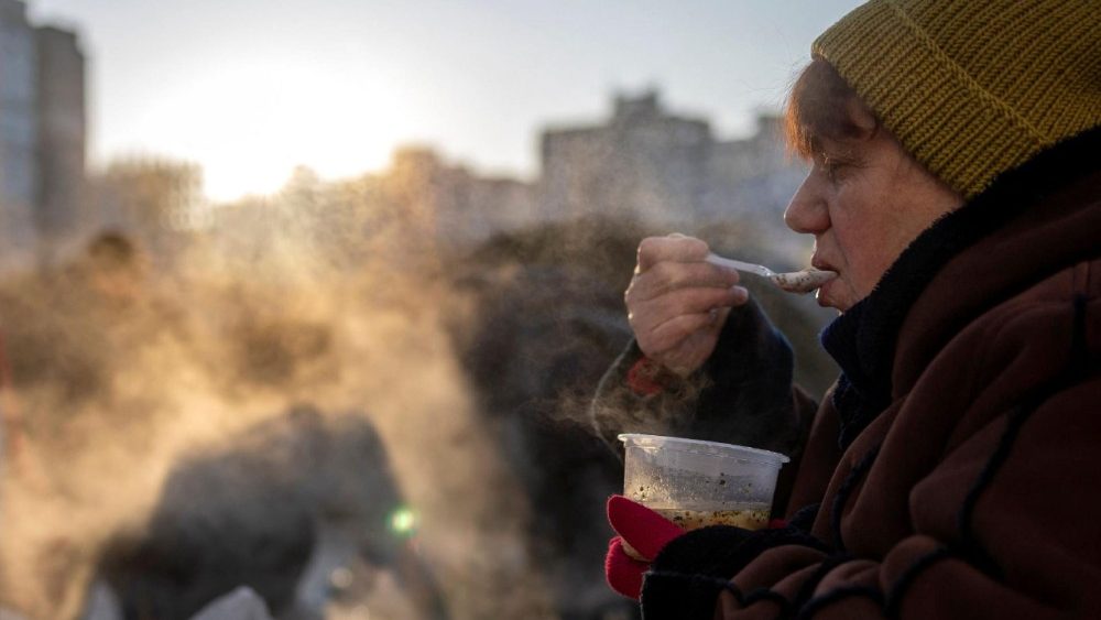 Uma mulher come sopa doada por um grupo de voluntários poloneses em um bairro que sofre com cortes de energia elétrica e aquecimento após recentes ataques russos à infraestrutura civil da Ucrânia, em temperaturas abaixo de zero, em Kiev, Ucrânia, em 3 de fevereiro de 2026. REUTERS/Thomas Peter