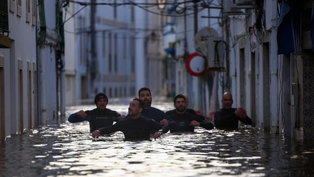 Um grupo de voluntários ao longo de rua alagada em Alcacer do Sal, Portugal, em 5 de fevereiro de 2026. REUTERS/Pedro Nunes