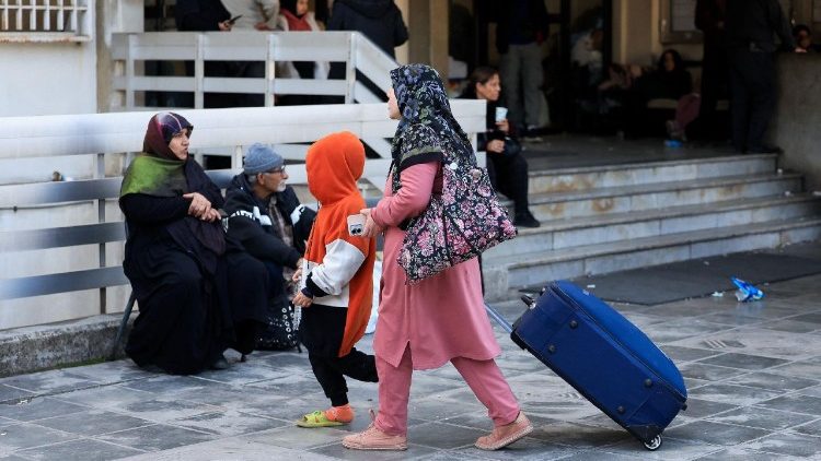 Mulher deslocada com uma criança caminha do lado de fora de uma escola transformada em abrigo, após a escalada entre o Hezbollah e Israel em meio ao conflito entre os EUA e Israel com o Irã, em Beirute, Líbano.