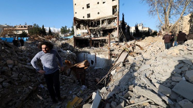 A man stands in the middle of the rubble left of a building that was destroyed by a strike, in Tehran