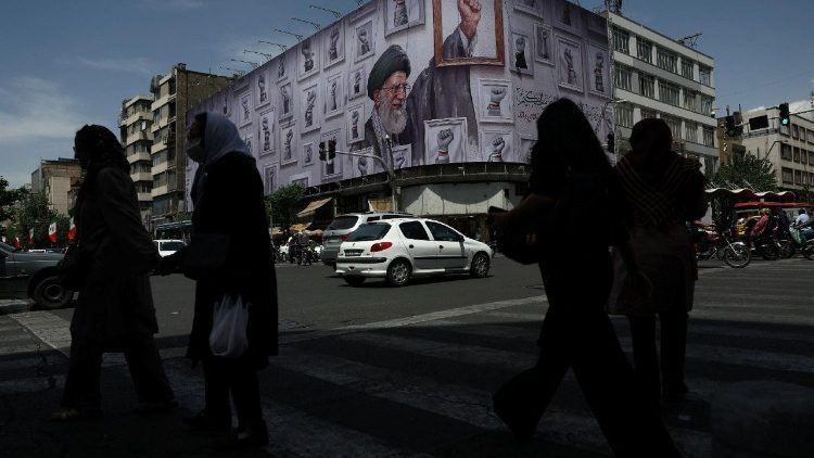 People walk near a billboard featuring an image of the late Supreme Leader of Iran, Ayatollah Ali Khamenei, in Tehran