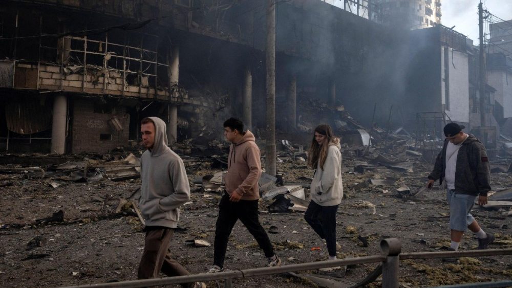 Jovens caminham ao lado de um prédio incendiado durante ataques noturnos com mísseis e drones russos, em meio à ofensiva da Rússia contra a Ucrânia, em Kiev, Ucrânia, 24 de maio de 2026. REUTERS/Thomas Peter