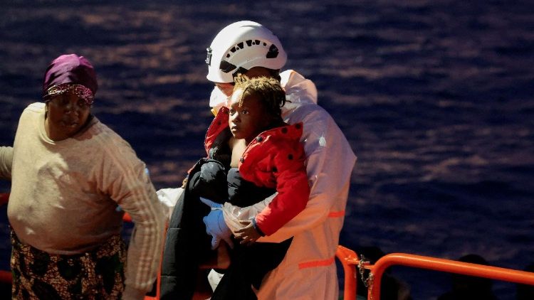  Un miembro del equipo de rescate ayuda a un ni&ntilde;o mientras los migrantes desembarcan de un barco de la Guardia Costera espa&ntilde;ola en el puerto de Arguinegu&iacute;n.