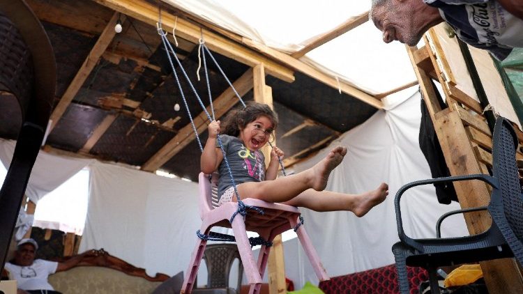Una ni&ntilde;a y su abuelo juegan dentro de una tienda de campa&ntilde;a utilizada como refugio en el paseo mar&iacute;timo de Beirut