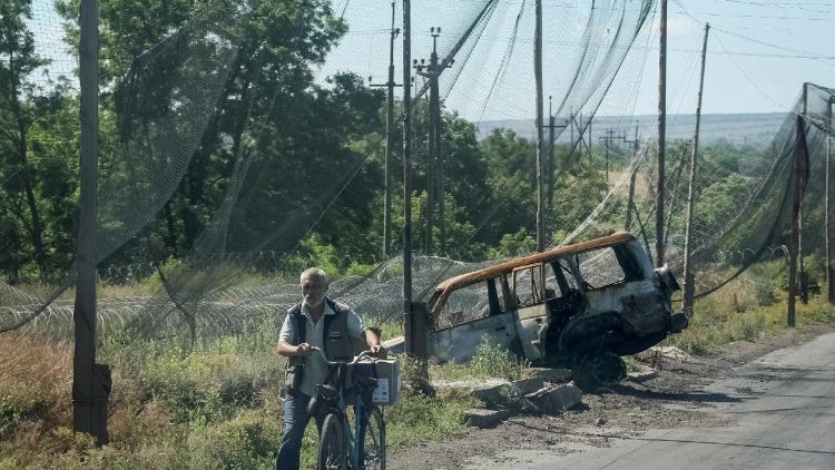 Um morador empurra uma bicicleta por uma rua coberta com redes antidrones e arame farpado instalado nas proximidades, em meio ao ataque da R&uacute;ssia &agrave; Ucr&acirc;nia, na cidade fronteiri&ccedil;a de Druzhkivka, na regi&atilde;o de Donetsk, Ucr&acirc;nia, em 21 de junho de 2026. REUTERS/Anatolii Stepanov