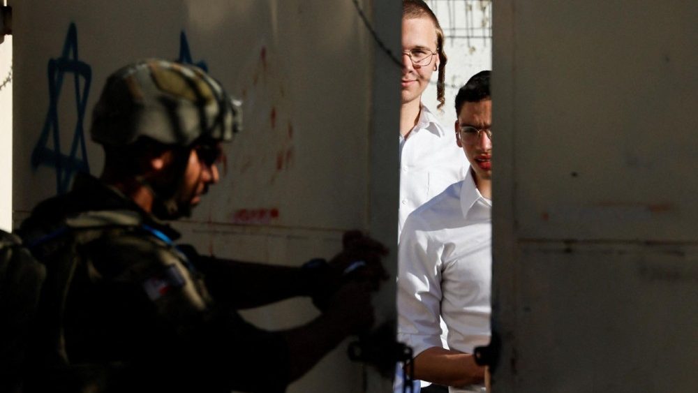 Um soldado israelense fecha um portão enquanto colonos israelenses participam de uma visita semanal em Hebron, na Cisjordânia ocupada por Israel, em 4 de julho de 2026. REUTERS/Mussa Qawasma