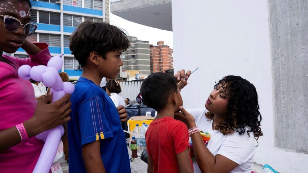 Uma voluntária pinta os rostos de crianças desabrigadas após o conjunto habitacional onde moram ter sido danificado pelos terremotos de 24 de junho, deixando os moradores impossibilitados de retornar aos seus apartamentos, em Caracas, Venezuela, 5 de julho de 2026. REUTERS/Marian Carrasquero