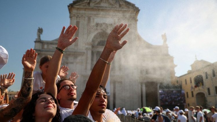 Jovens se refrescam com a névoa úmida diante da Basílica de Santa Maria dos Anjos,em Assis.