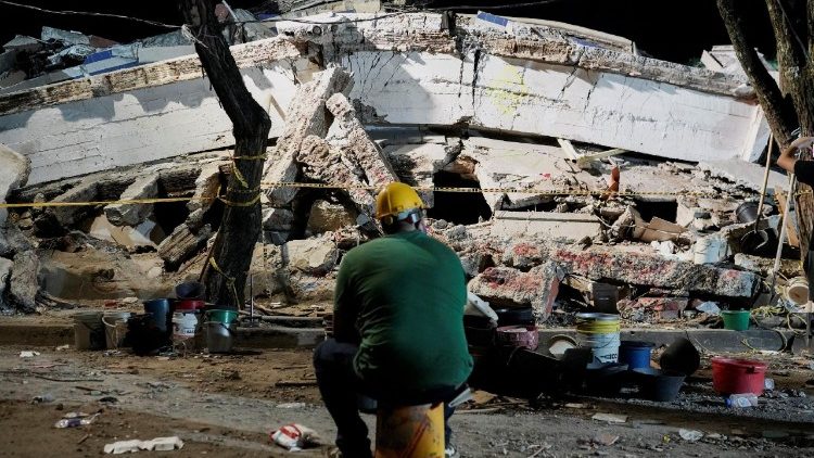 地震で倒壊した建物を前に座る男性　2026年8月11日　コロンビア西部カリ