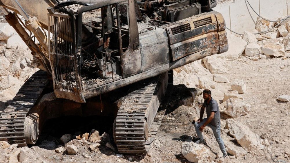 Një palestinez inspekton dëmet e shkaktuara nga një zjarr i vënë makinerive nga kolonët në një gurore pranë Hebronit. (Reuters/Mussa Qawasma)