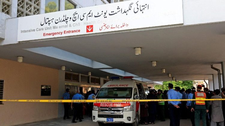 Police officers move past an ambulance outside an intensive care unit after a fire broke out at PIMS hospital in Islamabad