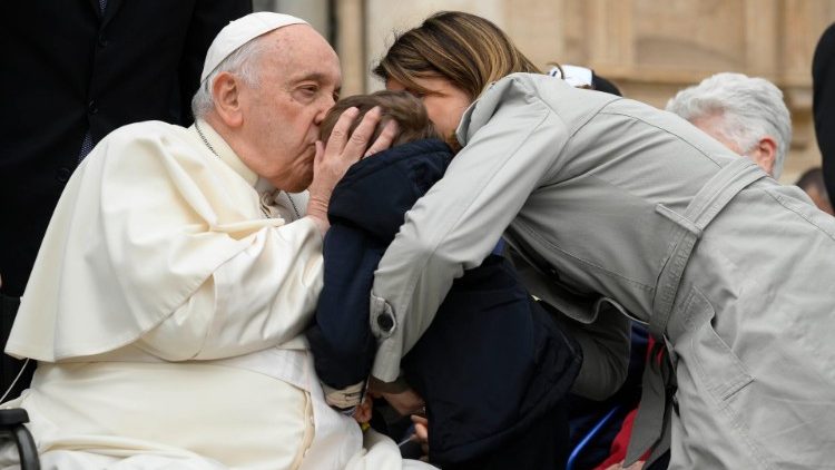 Papa Francesco bacia un bambino in Piazza San Pietro