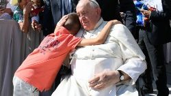 Pope Francis embraces a child at a Wednesday General Audience
