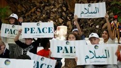 Pope Francis in between children holding up signs with the world "peace" written in various languages