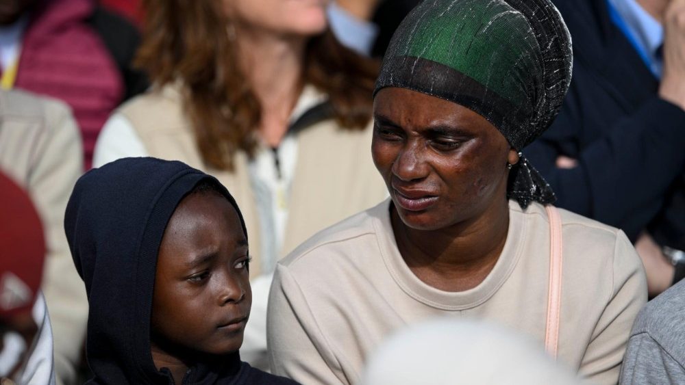 Una madre migrante con su hijo esperando al Papa en el centro Las Raíces