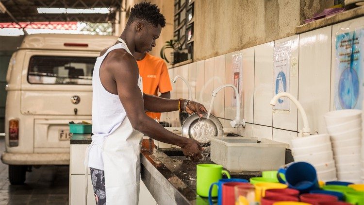 Depois de almoçar com pessoas de todo o mundo, John Ekow ajuda a lavar pratos na Casa do Migrante em São Paulo, Brasil (Giovanni Culmone/Global Solidarity Fund).