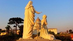 Em primeiro plano, estátuas de Nossa de Caravaggio e Joaneta. Ao fundo, Santuário de Caravaggio (Foto: Leandro Ávila)