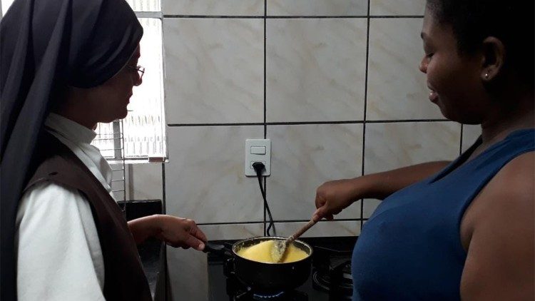 Eine Nonne hilft einer Frau bei der Essenszubereitung für die Kinder