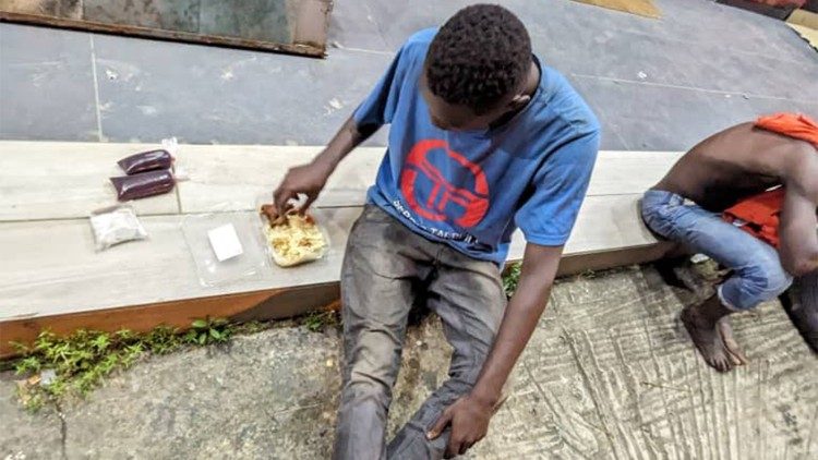 Un adolescent vivant dans la rue, ayant reçu de la nourriture donnée par un bienfaiteur