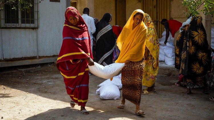 Two Sudanese women carry a bag of provisions distributed by WFP at Osma Degna School