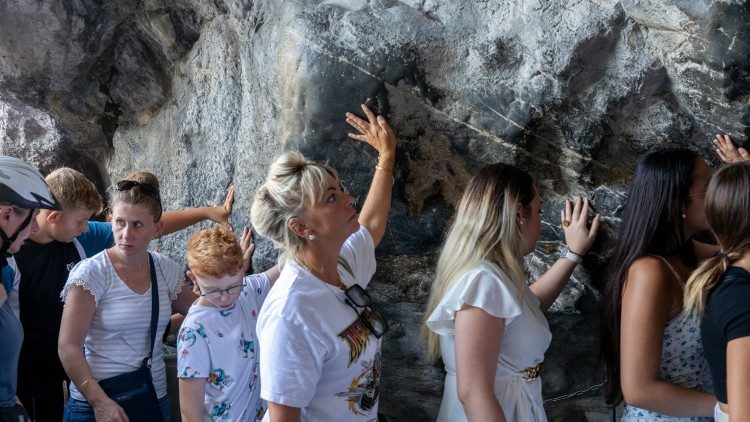 Pereginos tocam a rocha na Gruta das Aparições. (©Photo SNDL / Pierre Vincent)
