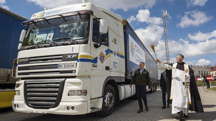 Patrick Kelly (C) watches as a priest blesses a Knights of Columbus truck bearing aid for Ukraine