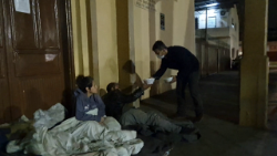 Ein Freiwilliger der Gruppe CES Mãos em Ação verteilt Mahlzeiten an Obdachlose, die vor einer Kirche in Canoas Zuflucht gefunden haben