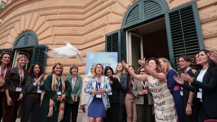 Guila lan&ccedil;ando a pomba da paz  enquanto traz um vestido com a escrita "paz" em diversas l&iacute;nguas. 