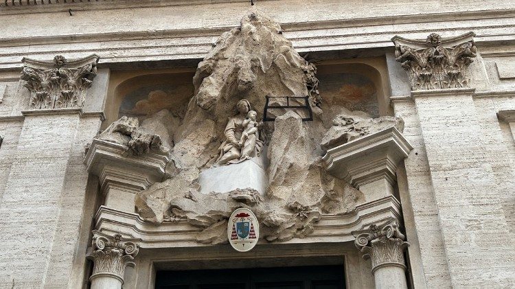 Facciata della chiesa di Santa Maria di Monserrato, altorilievo con rocce, la Vergine e il Bambino intento a segare il monte, tema iconografico della chiesa 