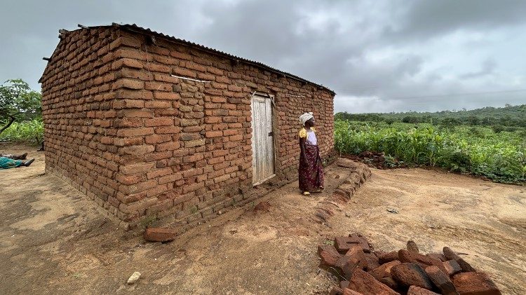 Tionge outside her house, the maize visible in the background