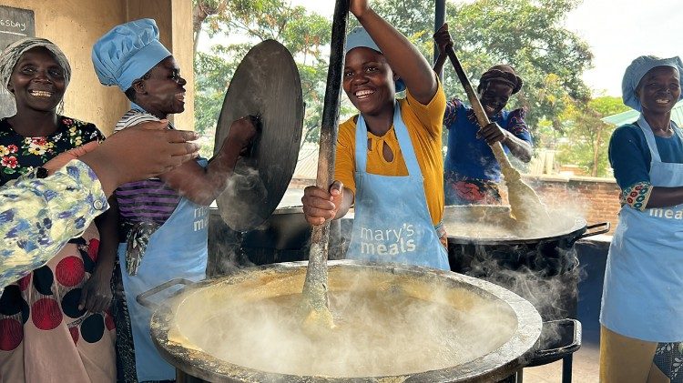 Volunteers from the local community prepare porridge for the children