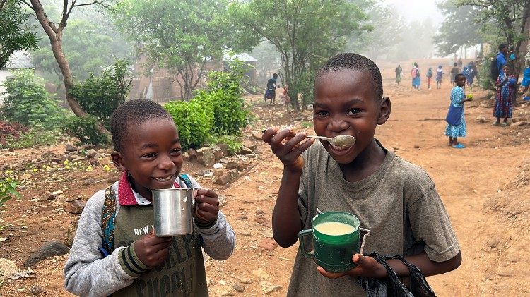 Two young boys eat their morning porridge 