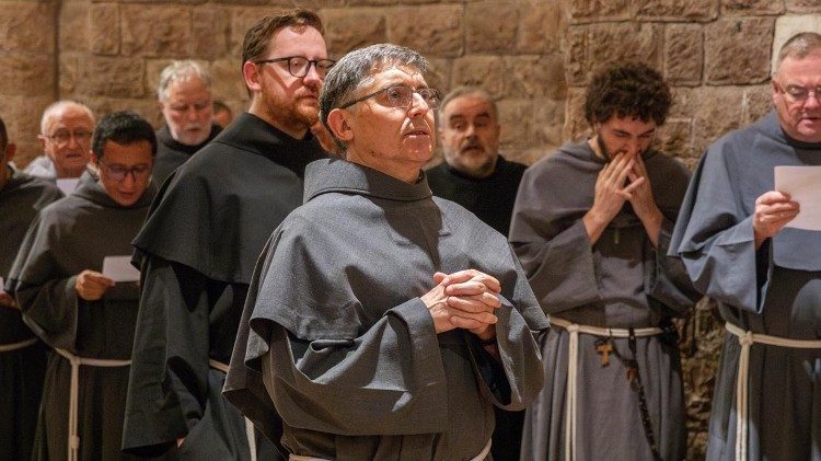 Fra Carlos Alberto Trovarelli (al centro) nella cripta della Basilica Inferiore di Assisi, prega davanti alla tomba di San Francesco