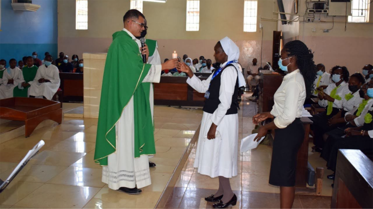 Sr. Juliana erhält während ihrer Beauftragung als Gebärdensprachdolmetscherin in der Erzdiözese Nairobi eine Kerze von P. Salvador Gomes MG, dem ehemaligen Gehörlosen-Seelsorger