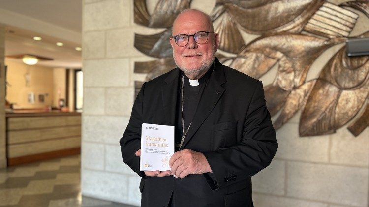 Kardinal Reinhard Marx mit einer Ausgabe der ersten Enzyklika von Papst Leo