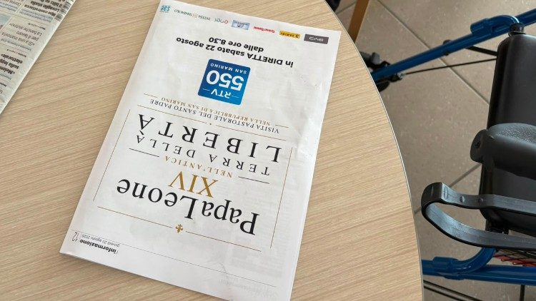 Seorang perempuan di tempat tinggal tersebut membaca surat kabar lokal yang mengumumkan kunjungan Paus.