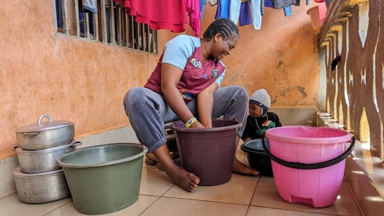 Adeline Nayah Tim washes her family's clothes using buckets and soap she received as part of ACER project implemented by Catholic Relief Services in northwestern Cameroon. In June 2023. She and her husband and children were forced to flee after their home was burnt down during a flare-up of armed conflict. The family was able to take refuge with a relative but arrived with no possessions. Photo by Emmanuel Joko, Caritas Bamenda