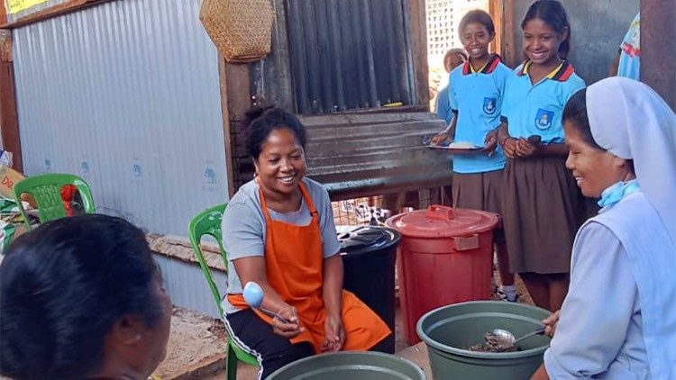 Einige Sch&uuml;lerinnen schauen bei der Essenszubereitung zu